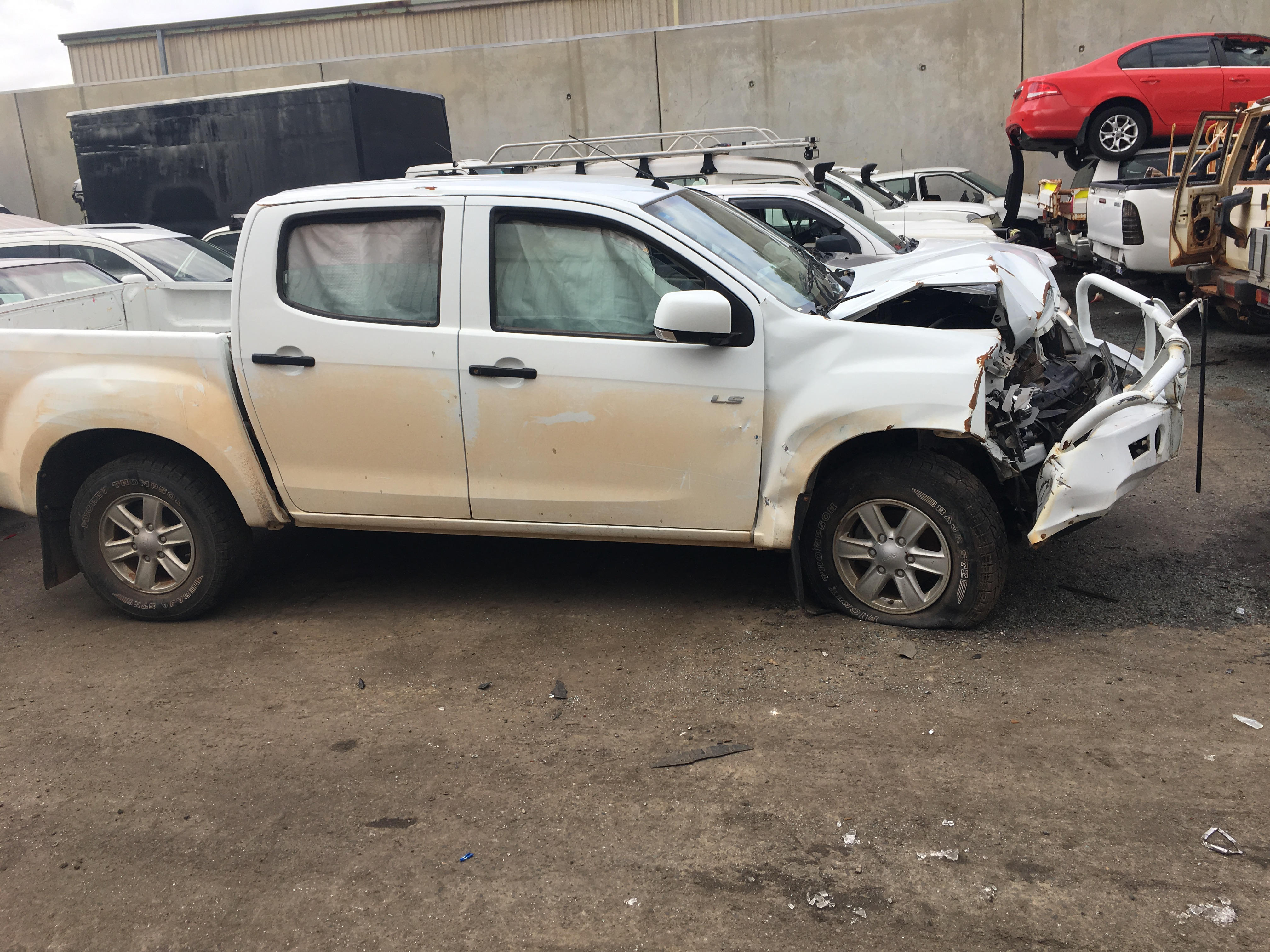 Damaged white pickup truck parked in a junkyard among other vehicles